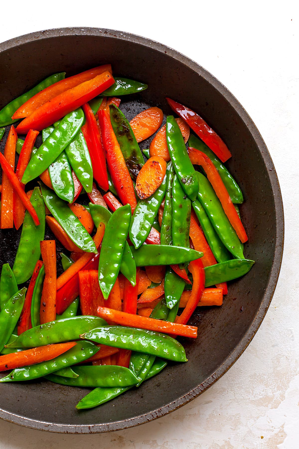 snow peas, carrots, and red pepper strips stir-frying in skillet.