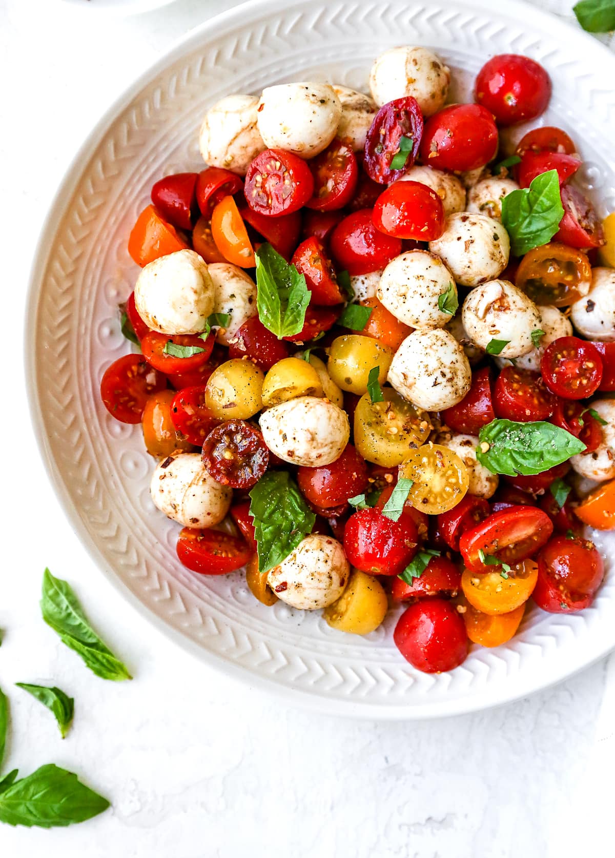 tomatoes, fresh mozzarella, and basil in bowl for caprese pasta salad.