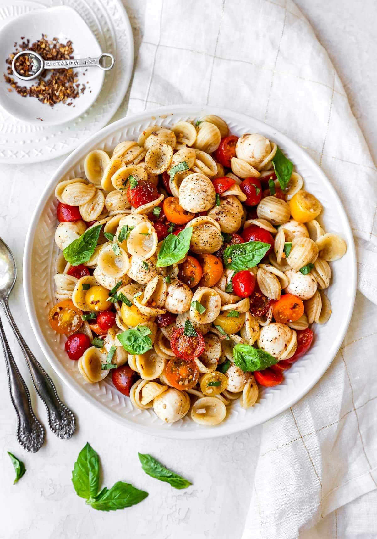 Caprese Pasta Salad in bowl with fresh basil. 