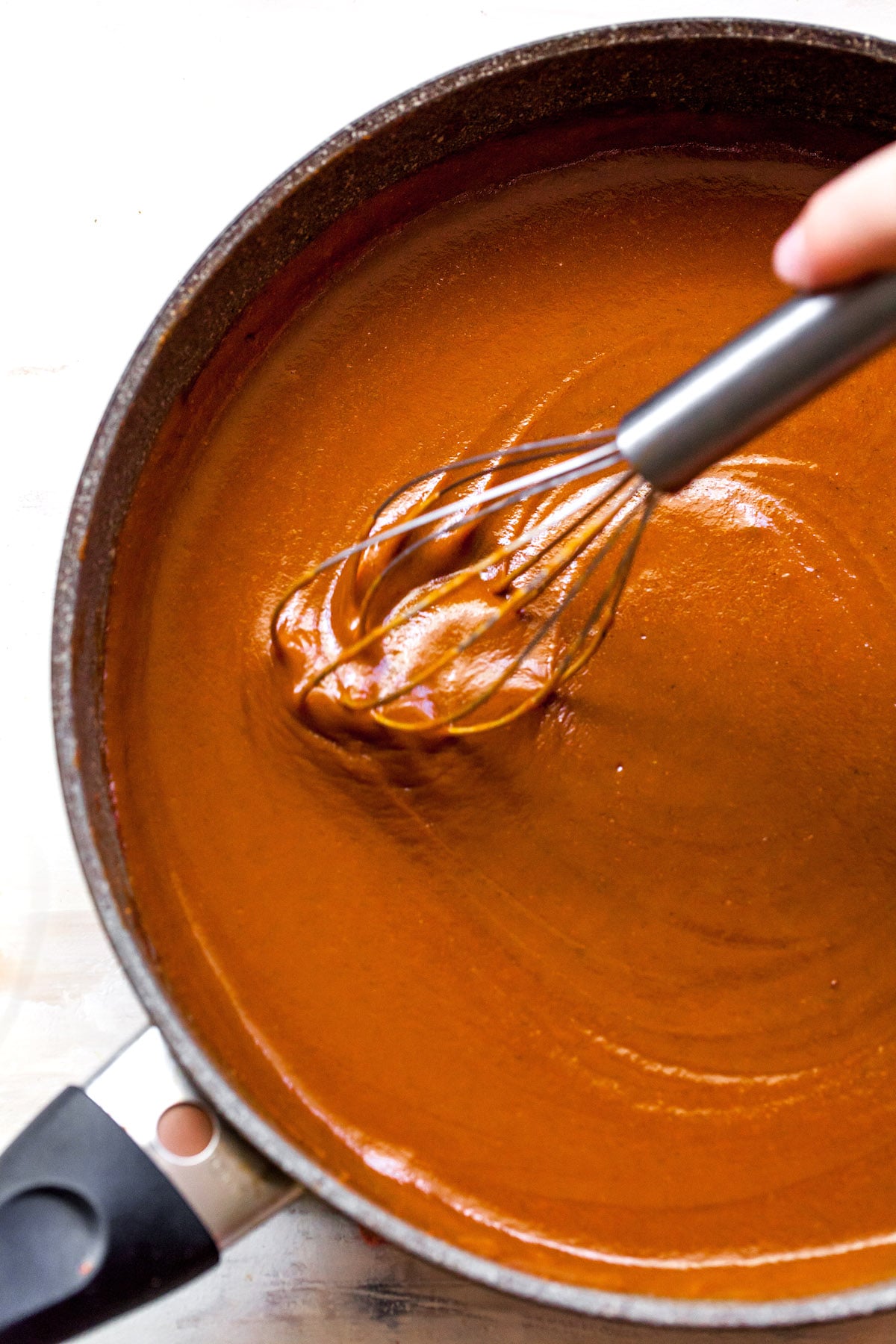making homemade enchilada sauce in pan with whisk.