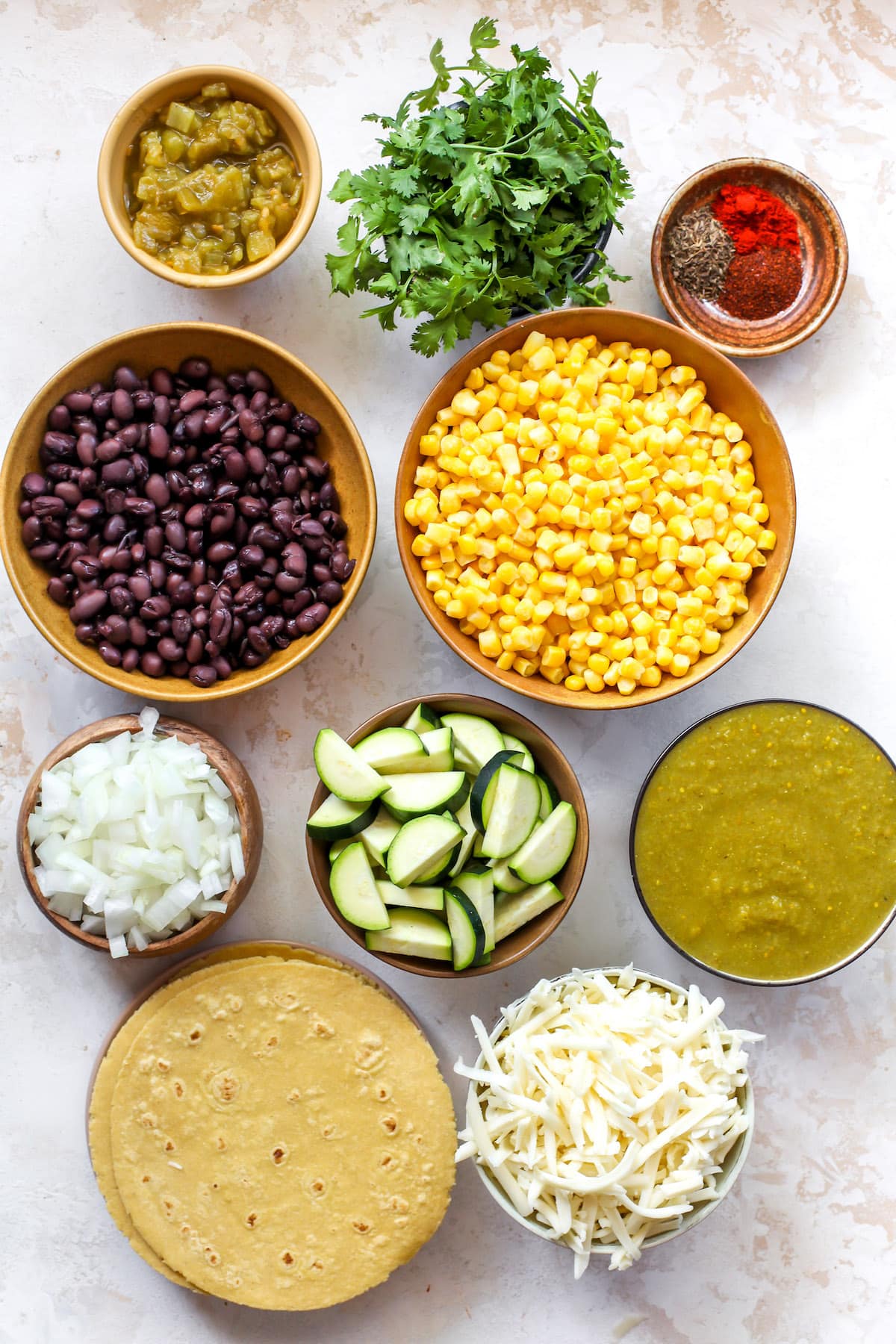 corn and zucchini enchiladas ingredients in bowls.