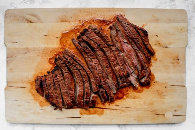 steak sliced on wood cutting board for steak salad.