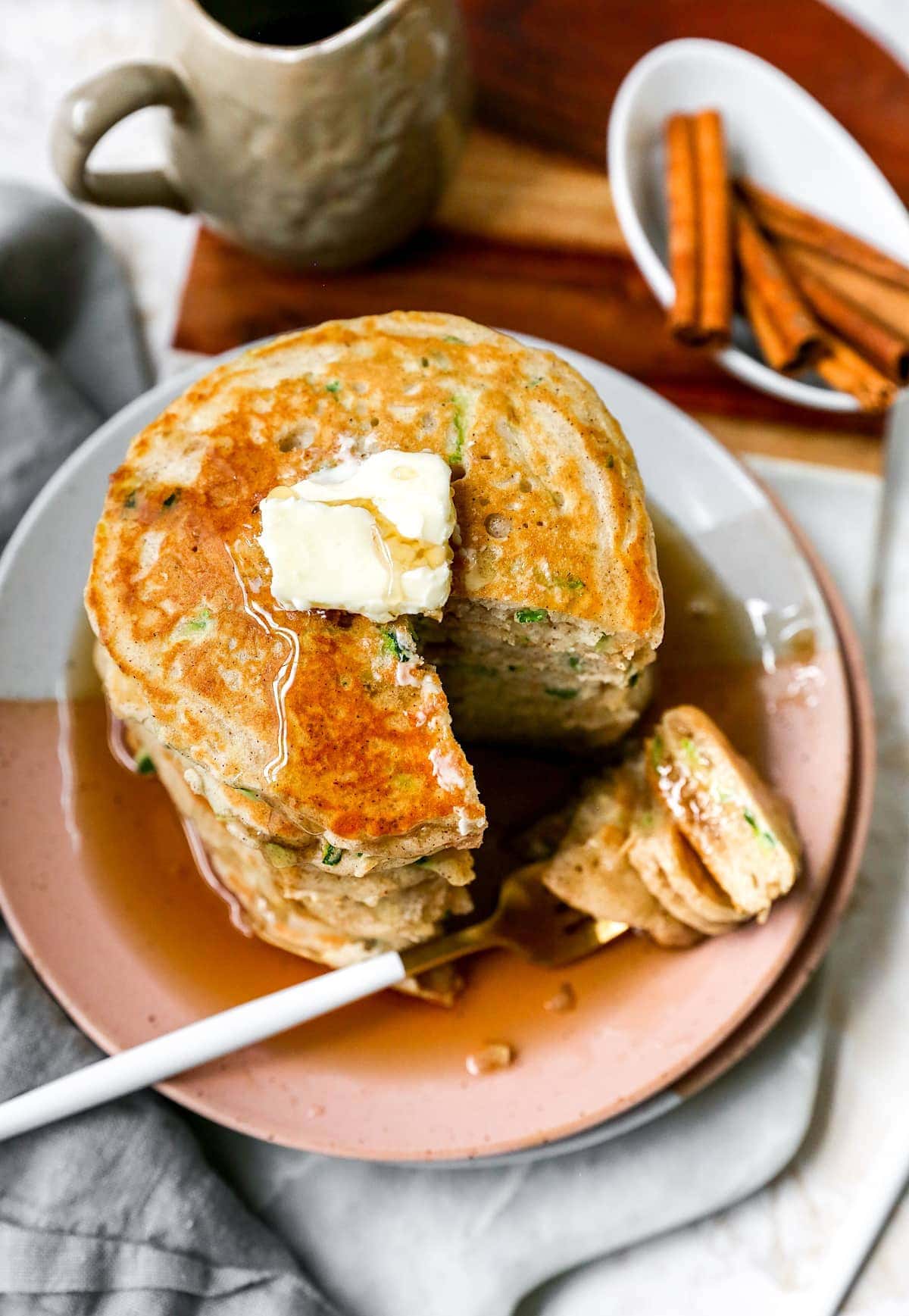 zucchini pancakes with butter and maple syrup on plate with fork.