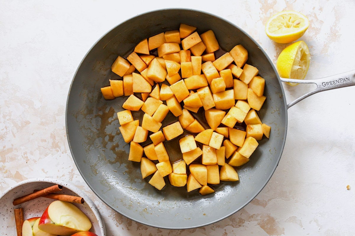 cinnamon apples cooking in skillet with brown sugar and cinnamon.