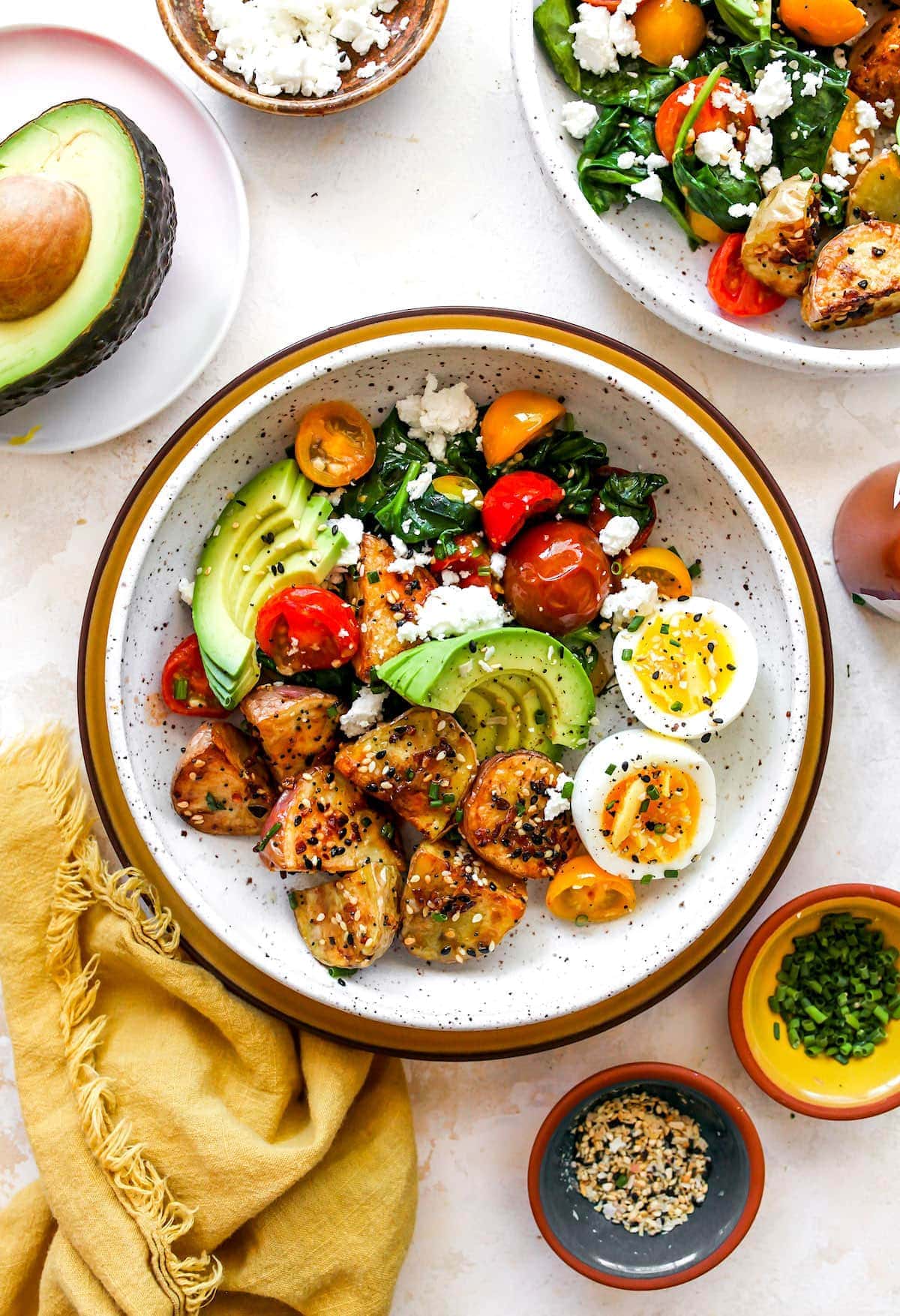 Healthy Savory Breakfast Bowl with eggs, potatoes, avocado, tomatoes, spinach, and cheese.