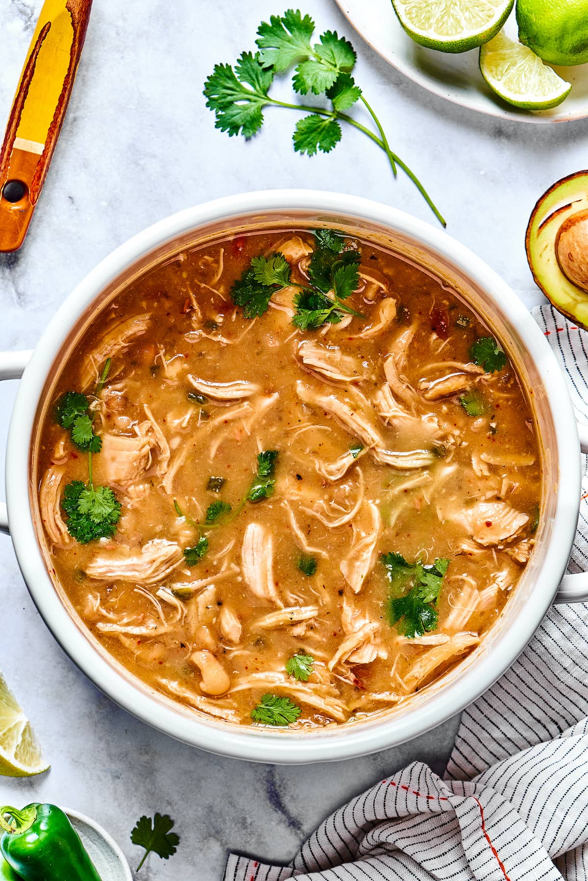 This comforting white chicken chili is easy to make with white beans, zesty seasonings, and rotisserie chicken. A favorite weeknight meal! Broth is added into a large pot with chicken chili ingredients.