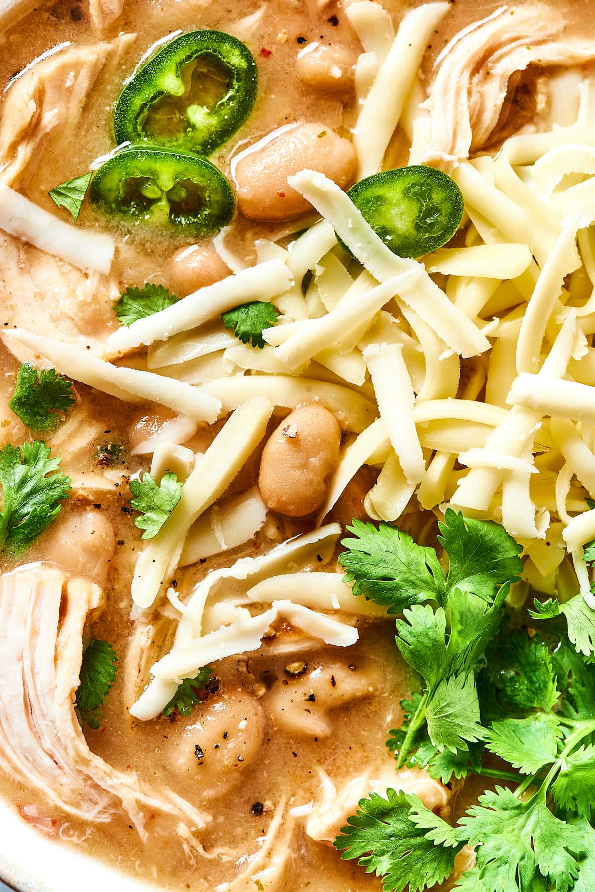 This comforting white chicken chili is easy to make with white beans, zesty seasonings, and rotisserie chicken. A favorite weeknight meal! Close up of white chicken chili garnished with fresh cilantro leaves.