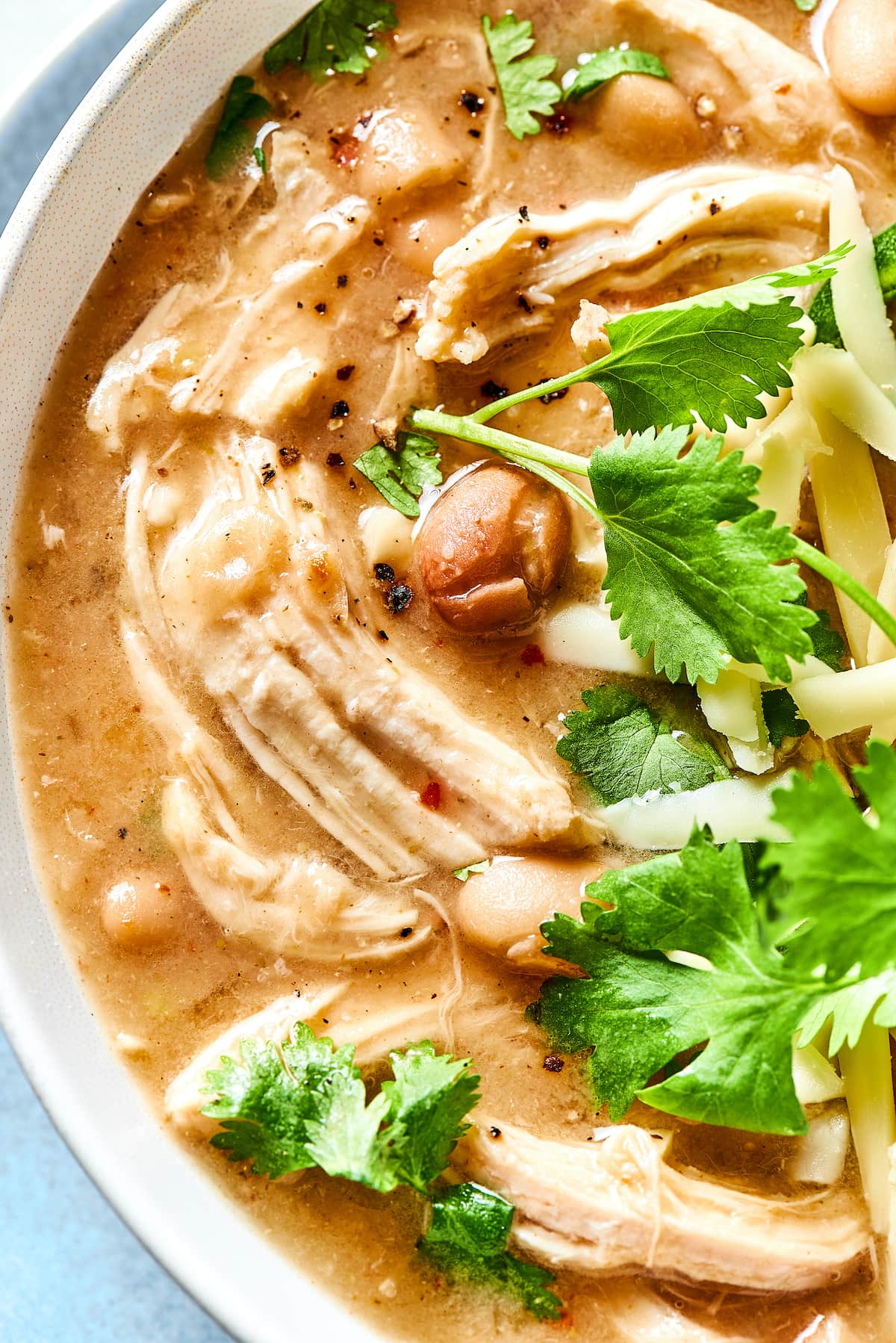 This comforting white chicken chili is easy to make with white beans, zesty seasonings, and rotisserie chicken. A favorite weeknight meal! Close up of white chicken chili garnished with fresh cilantro leaves.