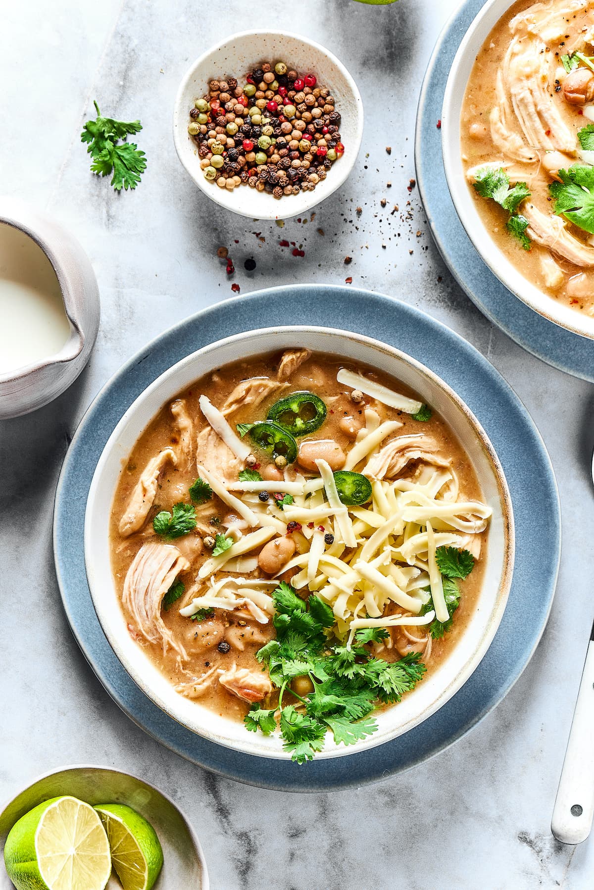 This comforting white chicken chili is easy to make with white beans, zesty seasonings, and rotisserie chicken. A favorite weeknight meal! A bowl of white chicken chili surrounded by chili toppings.