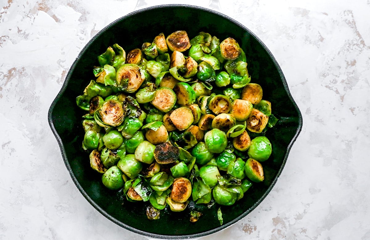 brussels sprouts cooking in cast iron skillet.