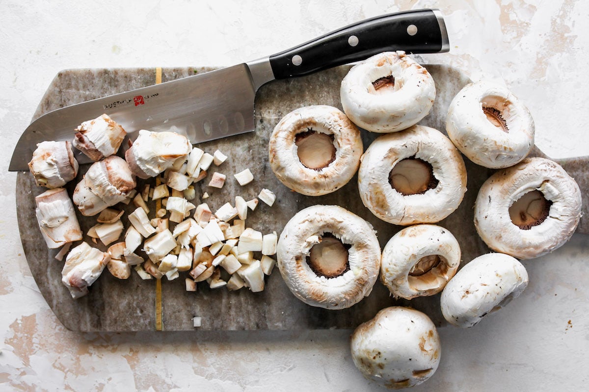 white mushrooms on cutting board with knife.