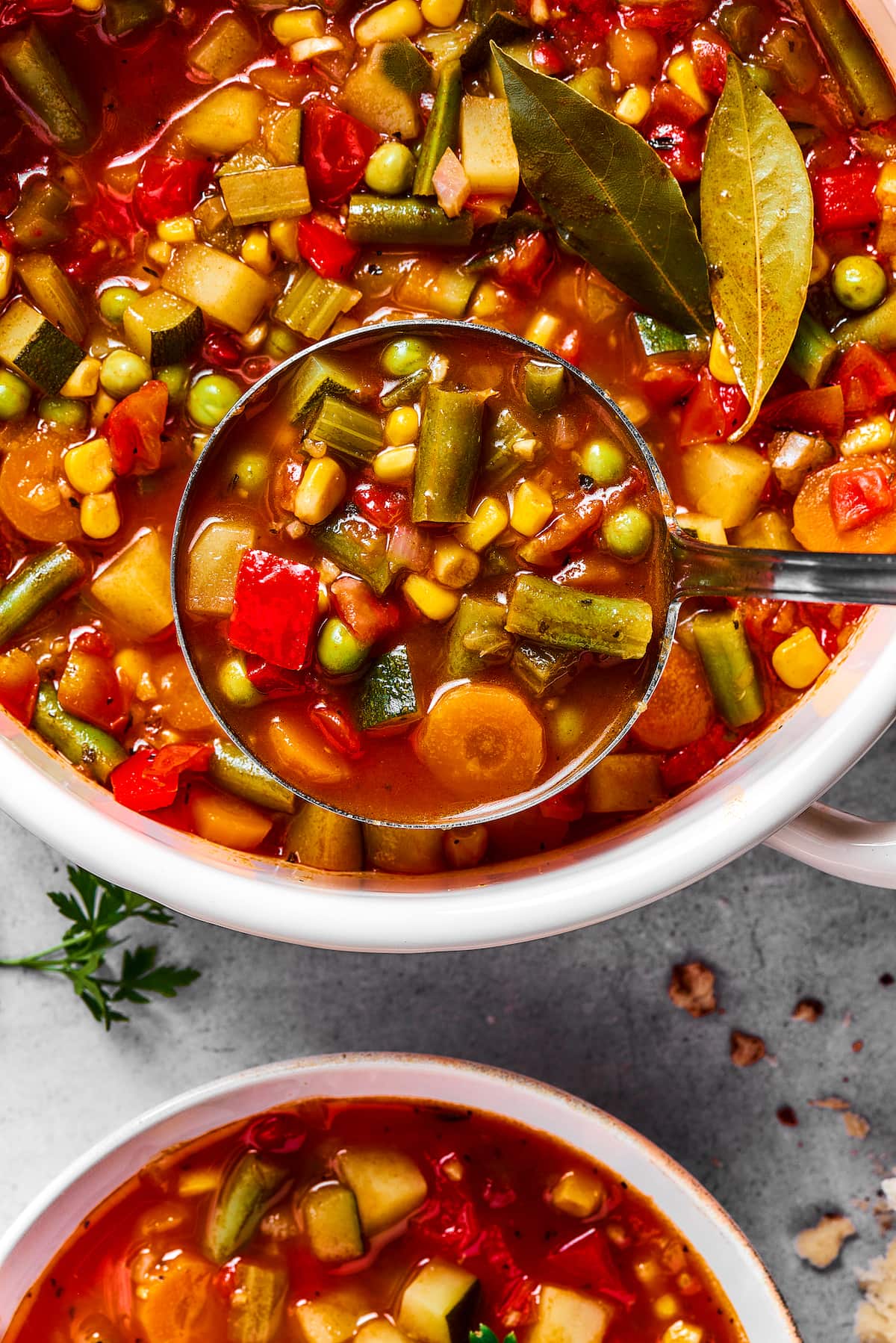 This comforting homemade vegetable soup recipe is a family favorite that's so much better than canned soup! Enjoy a bowl for lunch or dinner. Vegetable soup being ladled from a pot into a bowl.