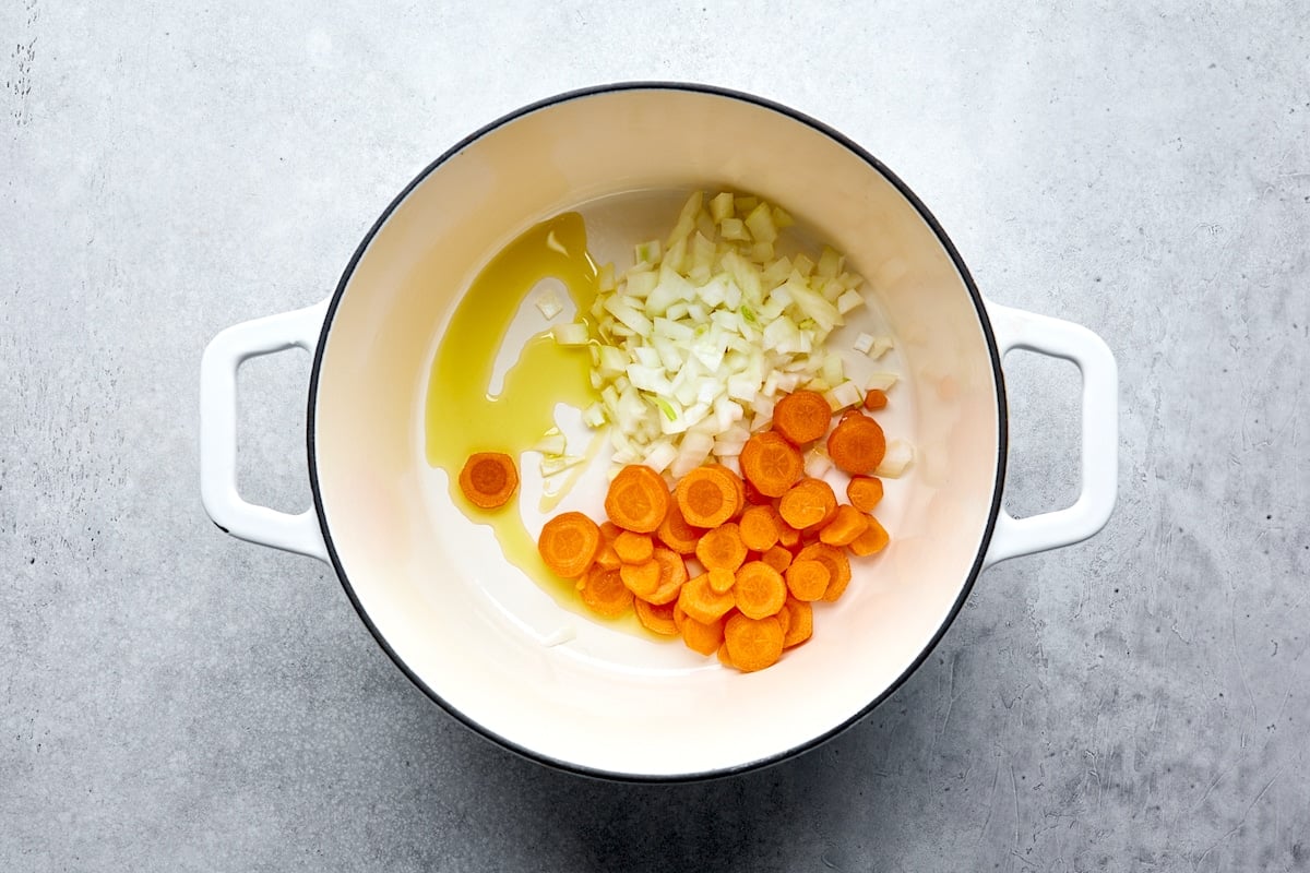 onion and carrots being sautéed in pot to make broccoli cheese soup.