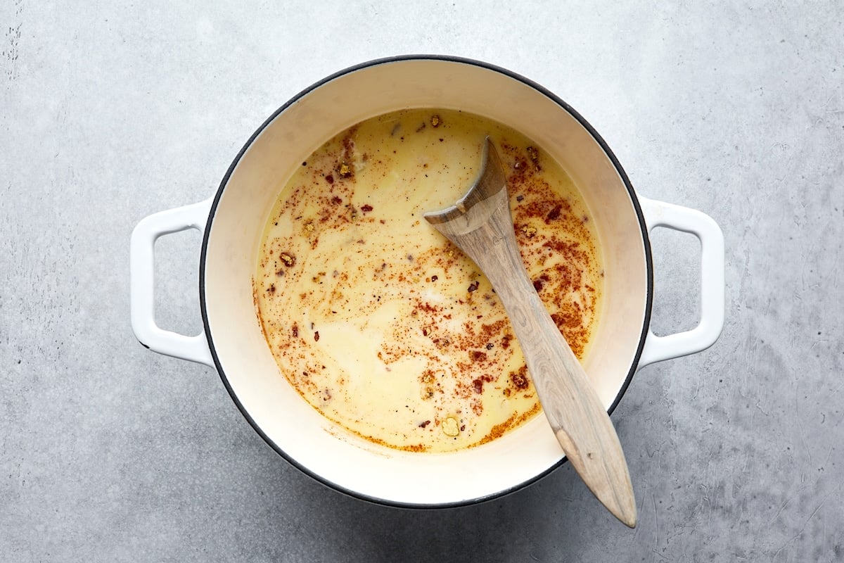 making broccoli cheese soup in pot with wooden spoon.