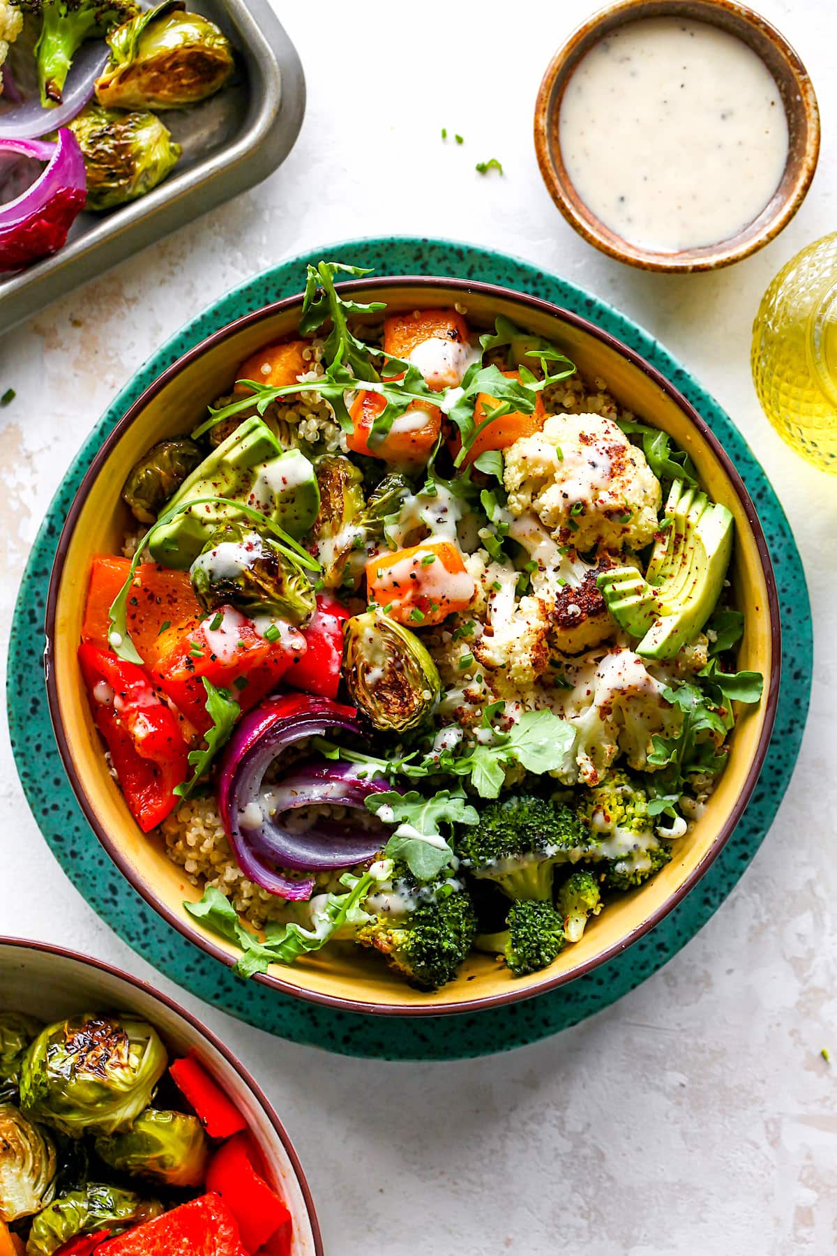 roasted vegetable bowl with quinoa, greens, avocado, and tahini dressing.