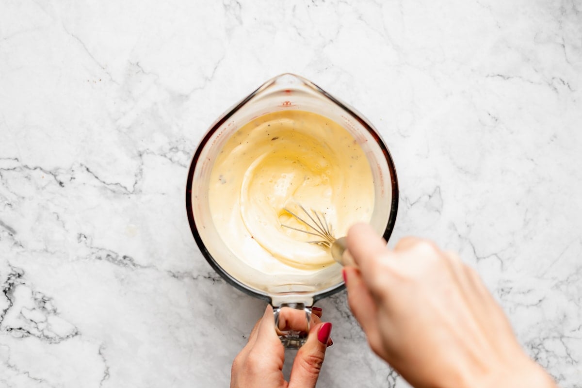 eggs and half and half being whisked together in a liquid measuring cup.