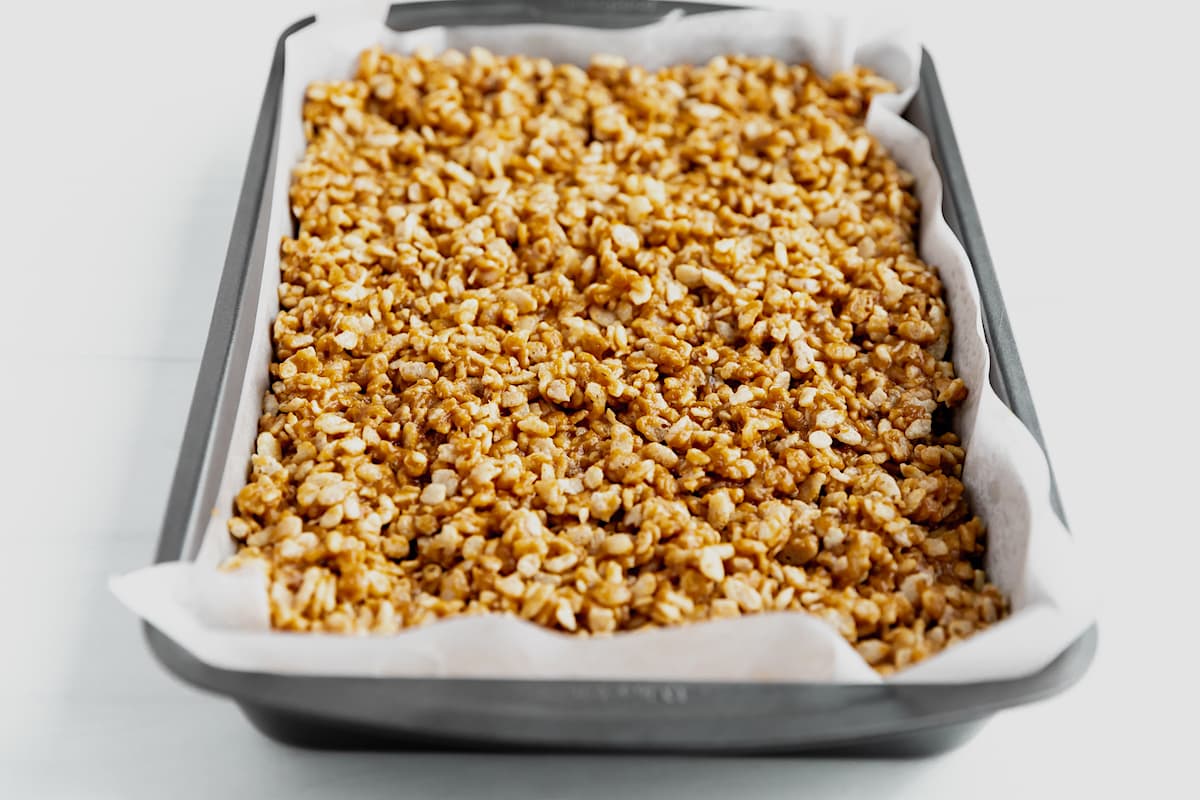 scotcheroos pressed into pan with parchment paper.