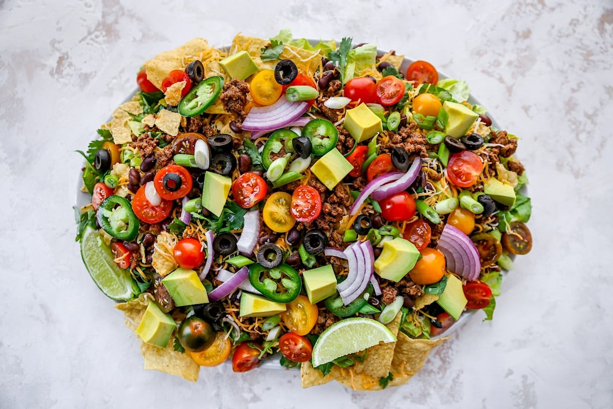 taco salad on platter with taco meat and toppings.