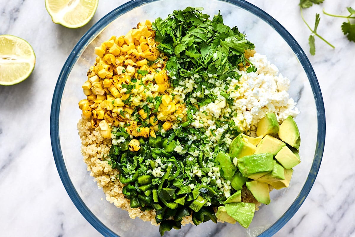 corn and avocado quinoa salad ingredients in mixing bowl.