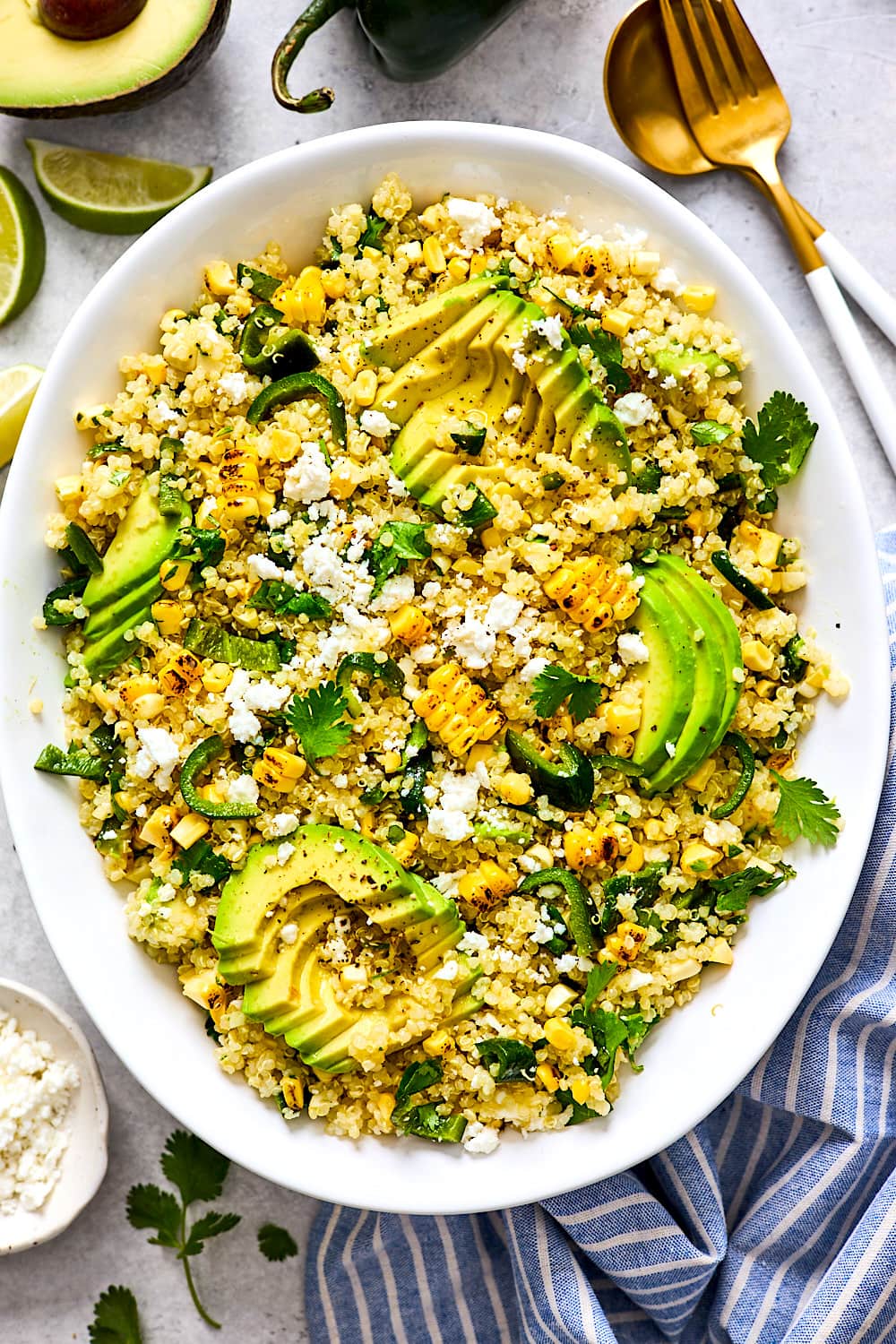 corn avocado quinoa salad with avocado and cotija cheese on big white platter.