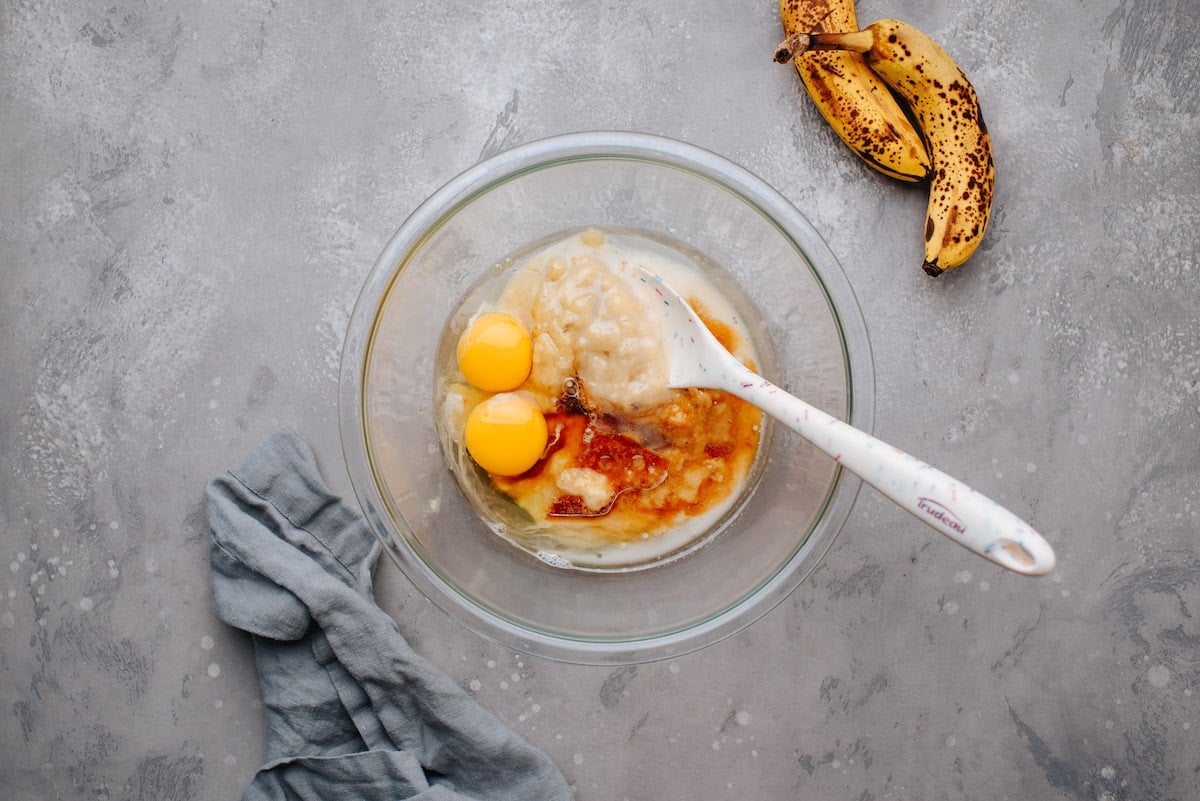mixing mashed banana, eggs, and liquid ingredients in mixing bowl.
