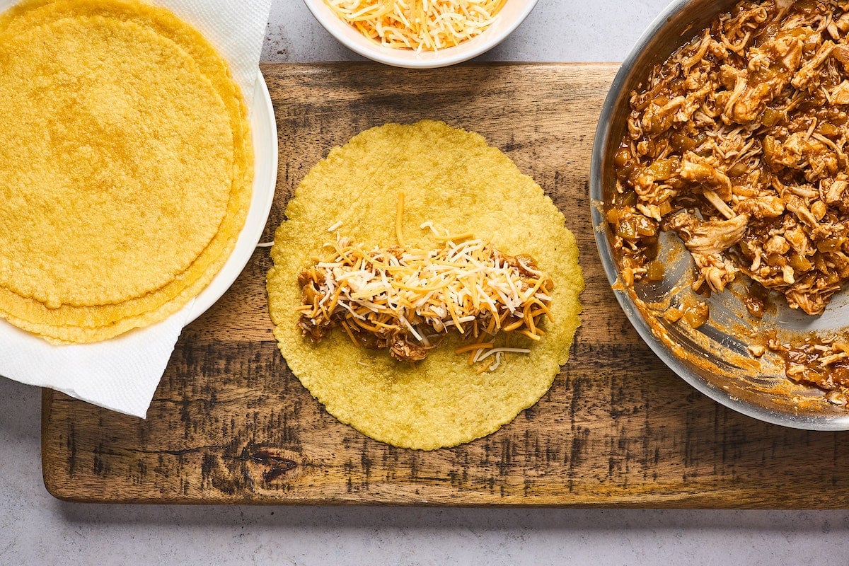 rolling chicken enchiladas in corn tortilla.