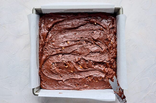 chocolate fudge spread in a baking pan with parchment paper.