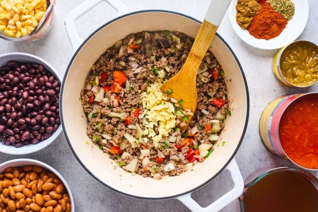 taco soup ingredients in a pot with wooden spoon.