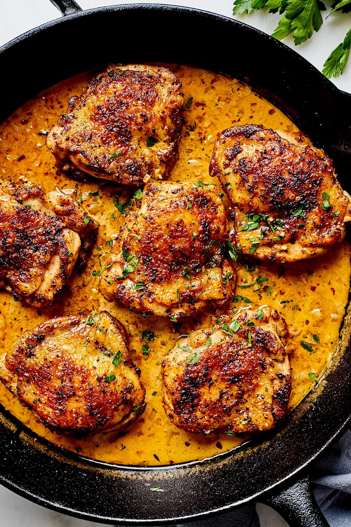 skillet chicken thighs in sauce in cast iron skillet.