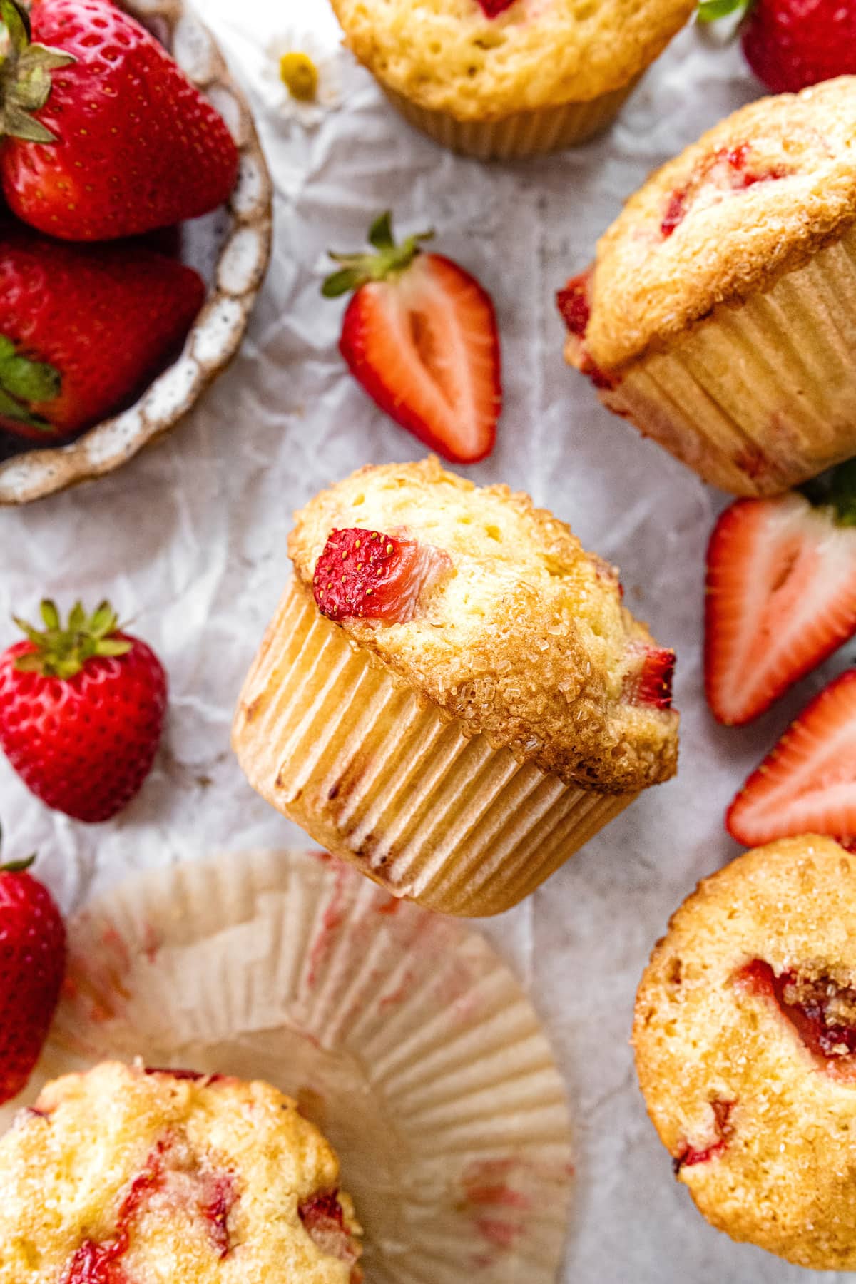 strawberry muffins in paper liner with fresh strawberries.