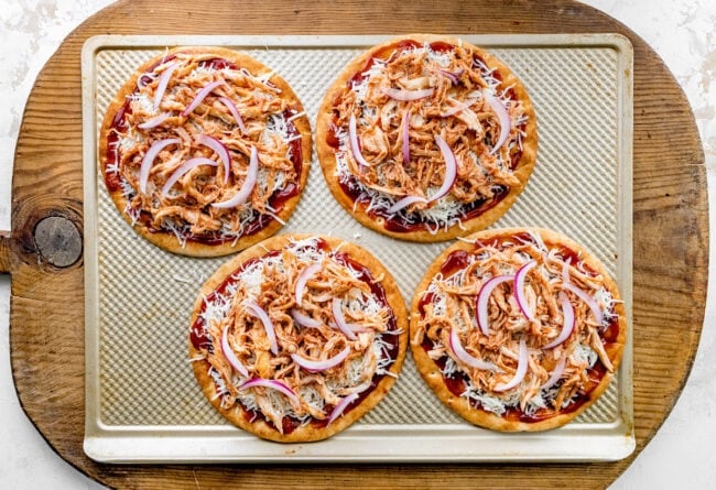 BBQ chicken pita pizzas unbaked on baking sheet.