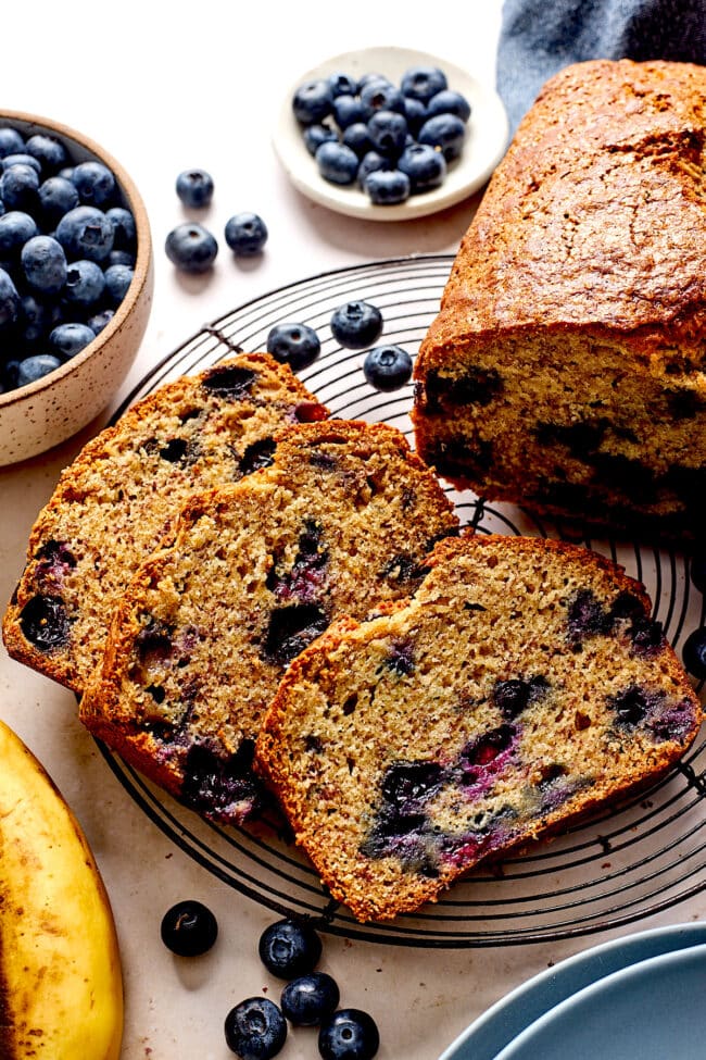 blueberry banana bread cut in slices on cooling rack.