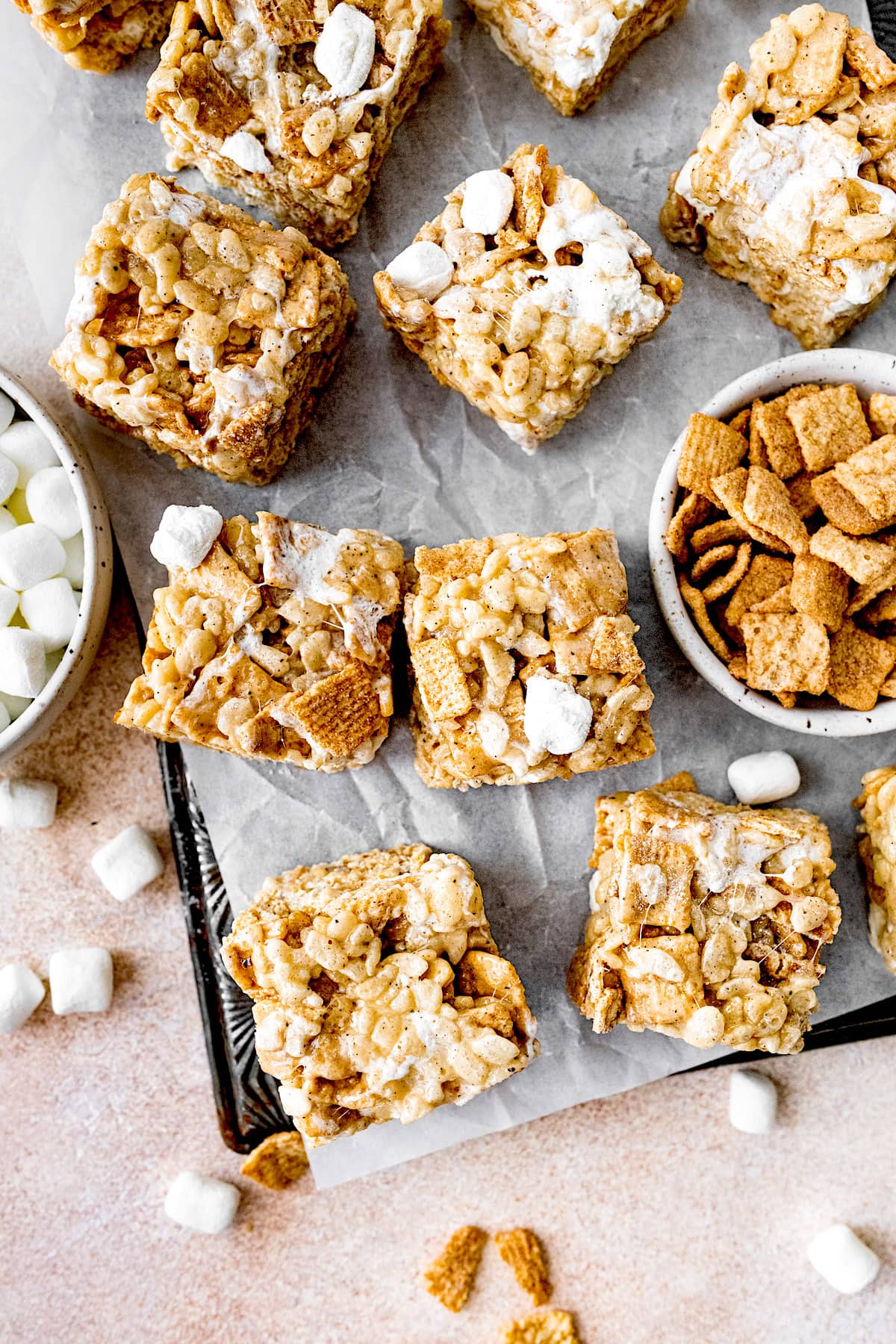 cinnamon toast rice krispie treats on pan with parchment paper and mini marshmallows.