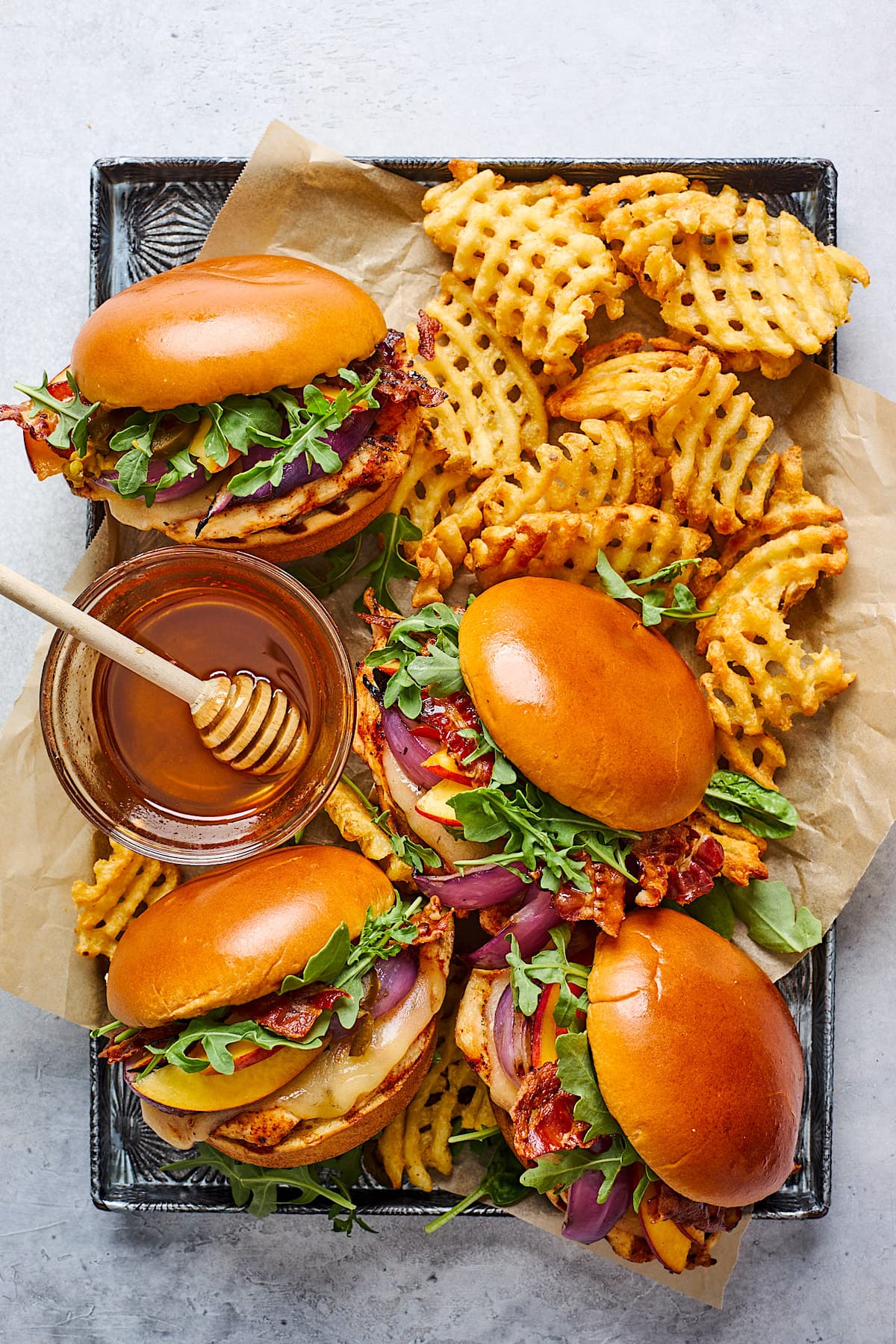 grilled chicken sandwiches with fries and honey on tray.