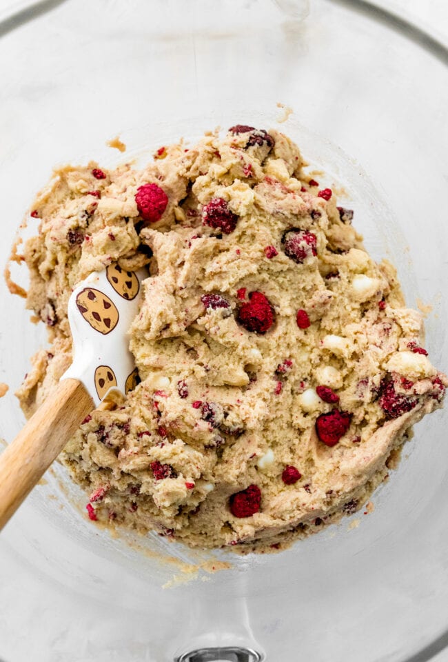 white chocolate raspberry cookie dough in bowl with spatula.