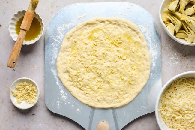 pizza dough on pizza peel with olive oil and garlic.