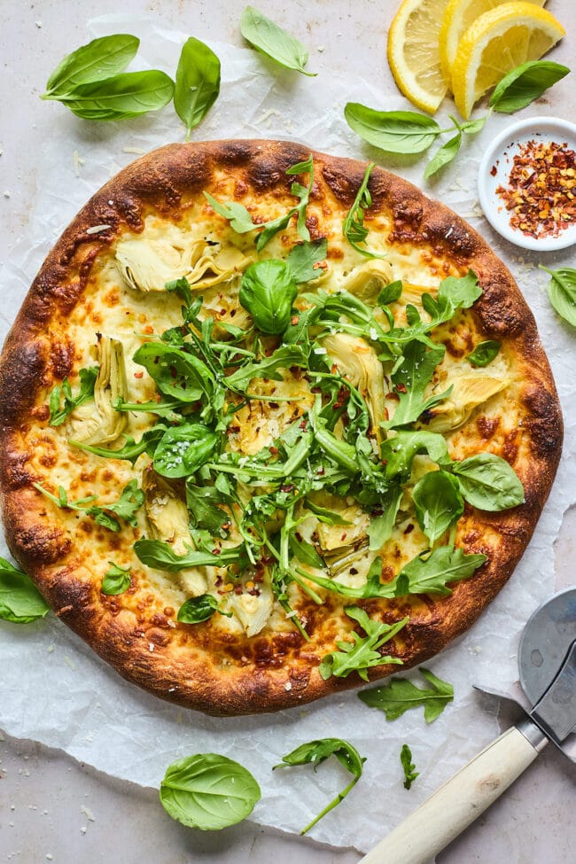 lemon artichoke arugula pizza on parchment paper.