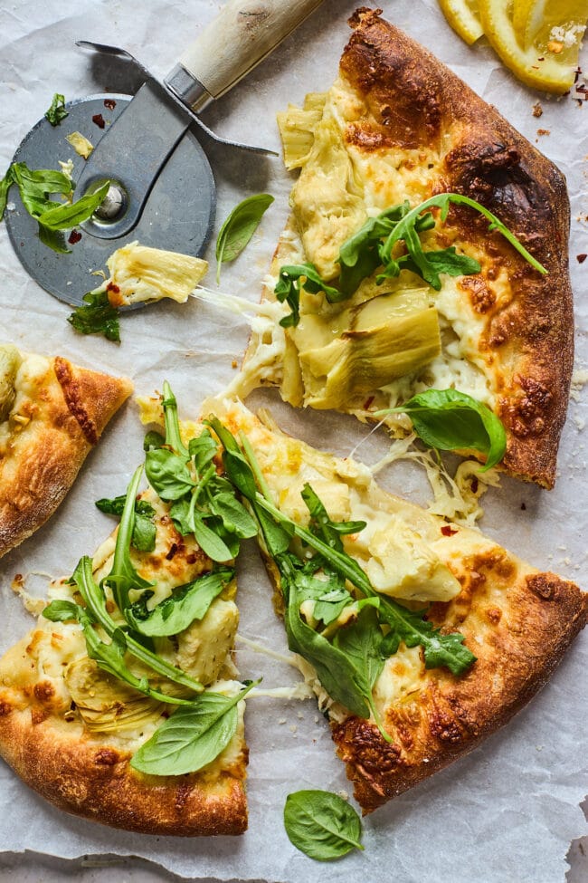 lemon artichoke arugula pizza cut in slices with a pizza cutter.
