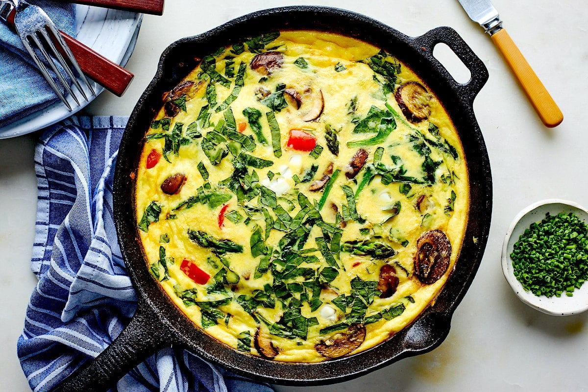 cottage cheese frittata in cast iron skillet with tea towel.
