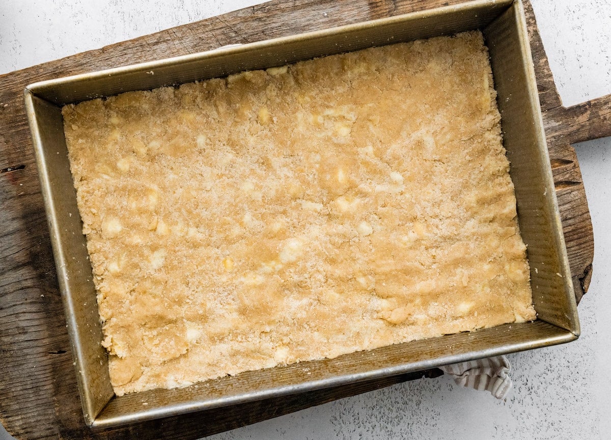 dough pressed in 9x13-inch pan for salted caramel apple crumb bars.