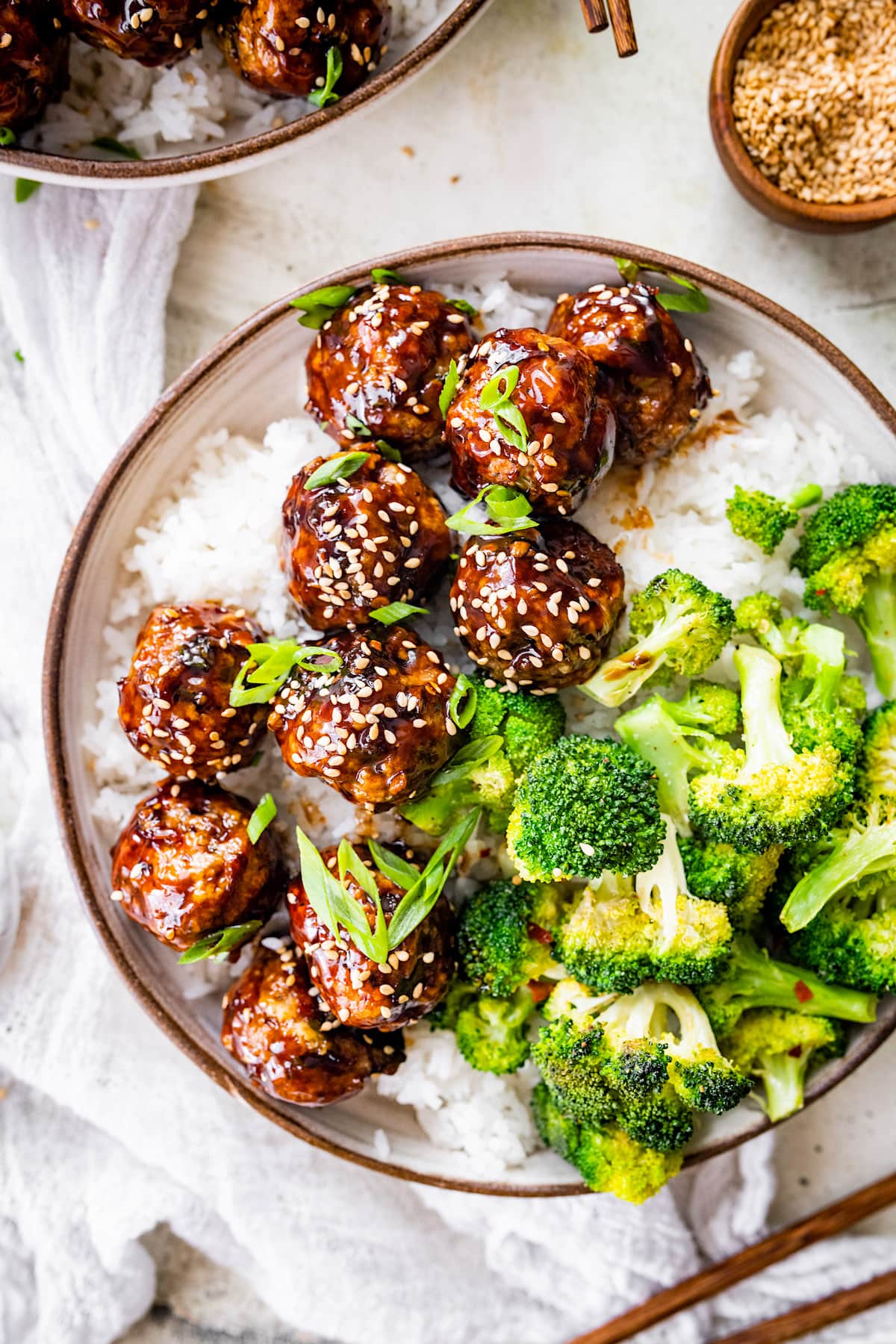 teriyaki chicken meatballs with sesame seeds in bowl with white rice and broccoli.