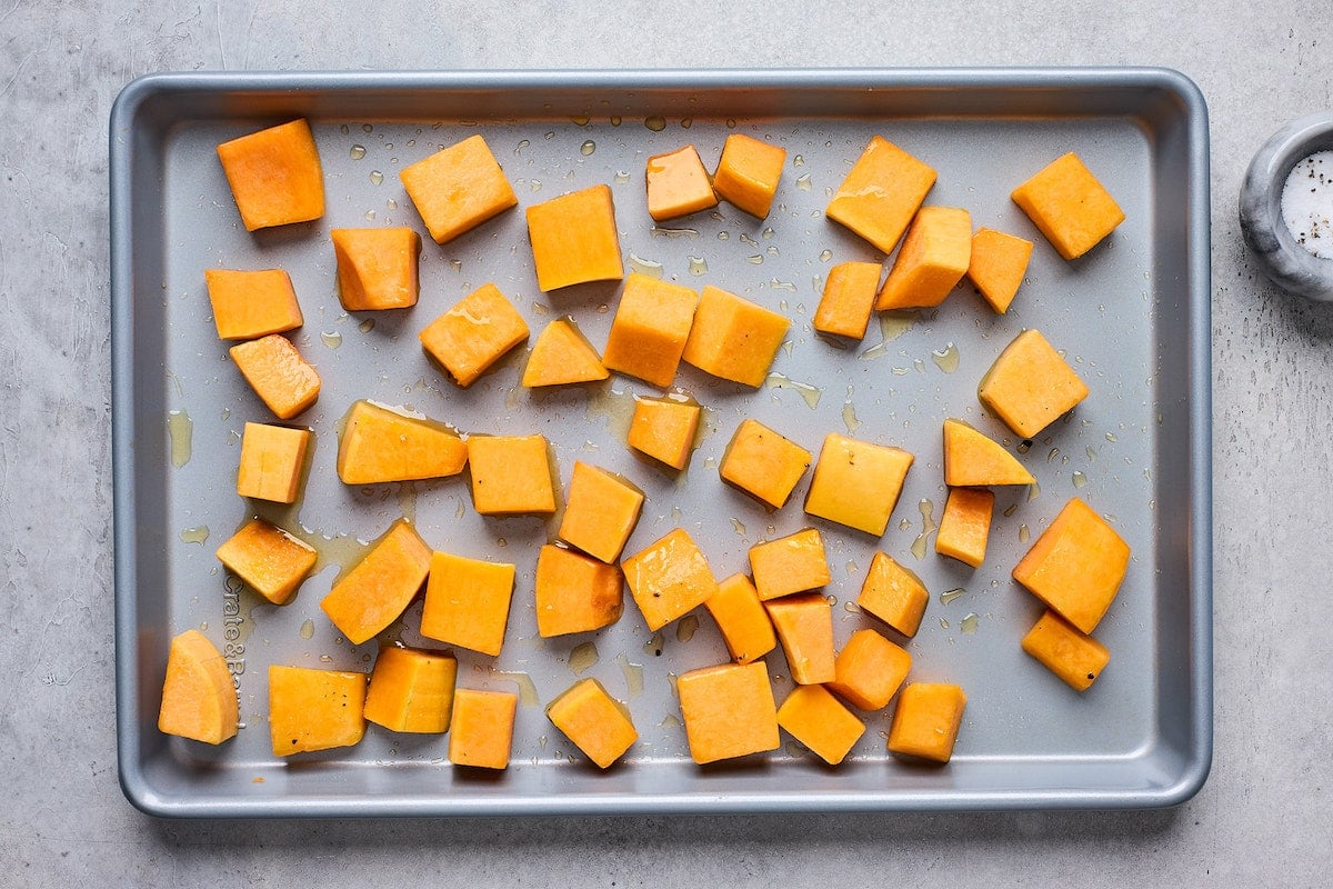 butternut squash on baking sheet drizzled with olive oil.