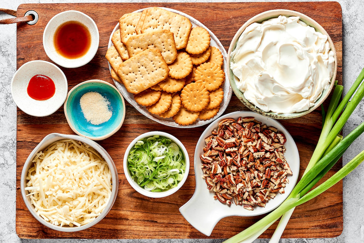 cheese ball ingredients in bowls on wood cutting board.