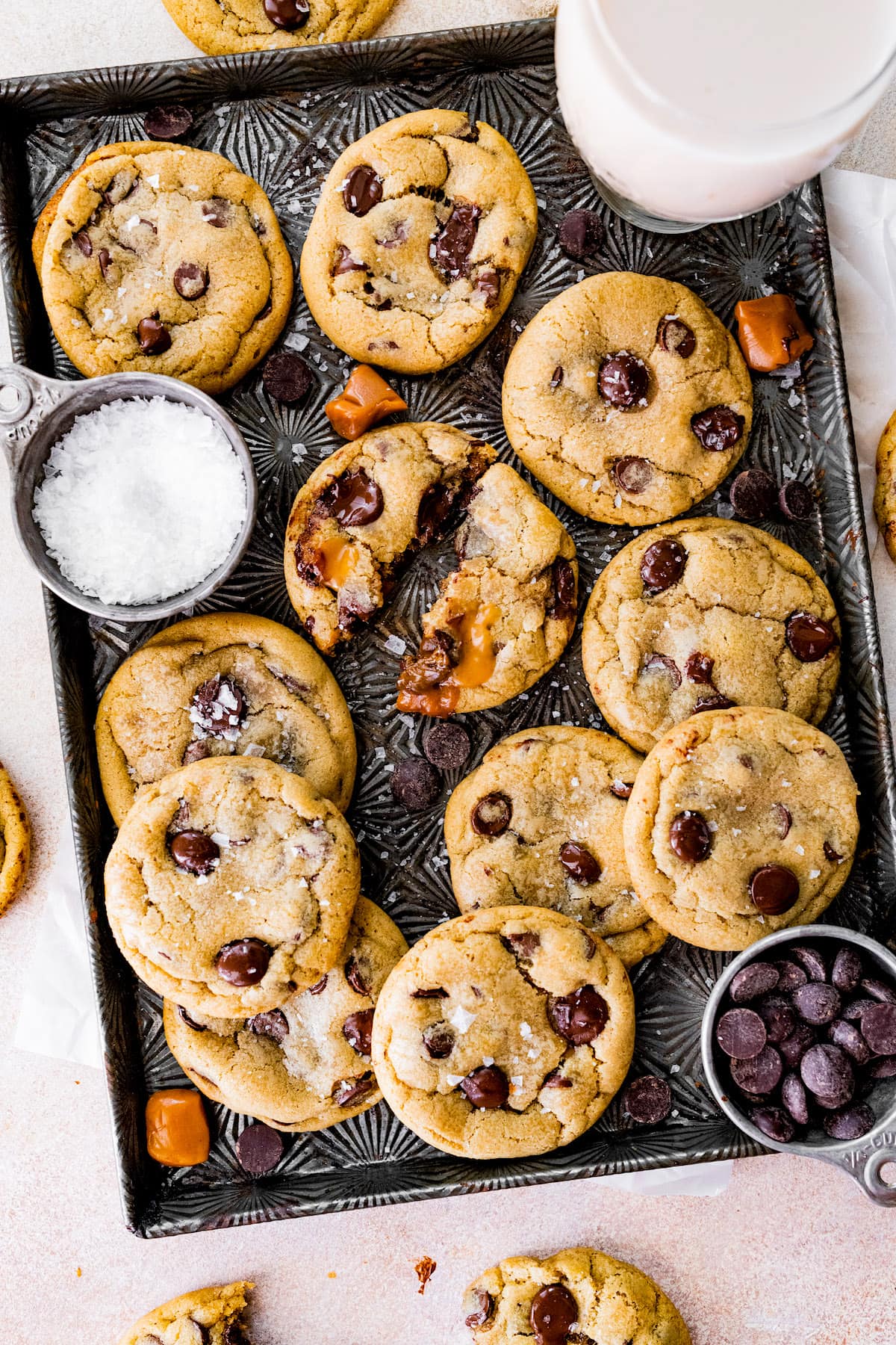 salted caramel chocolate chip cookies on baking pan with caramels and sea salt.