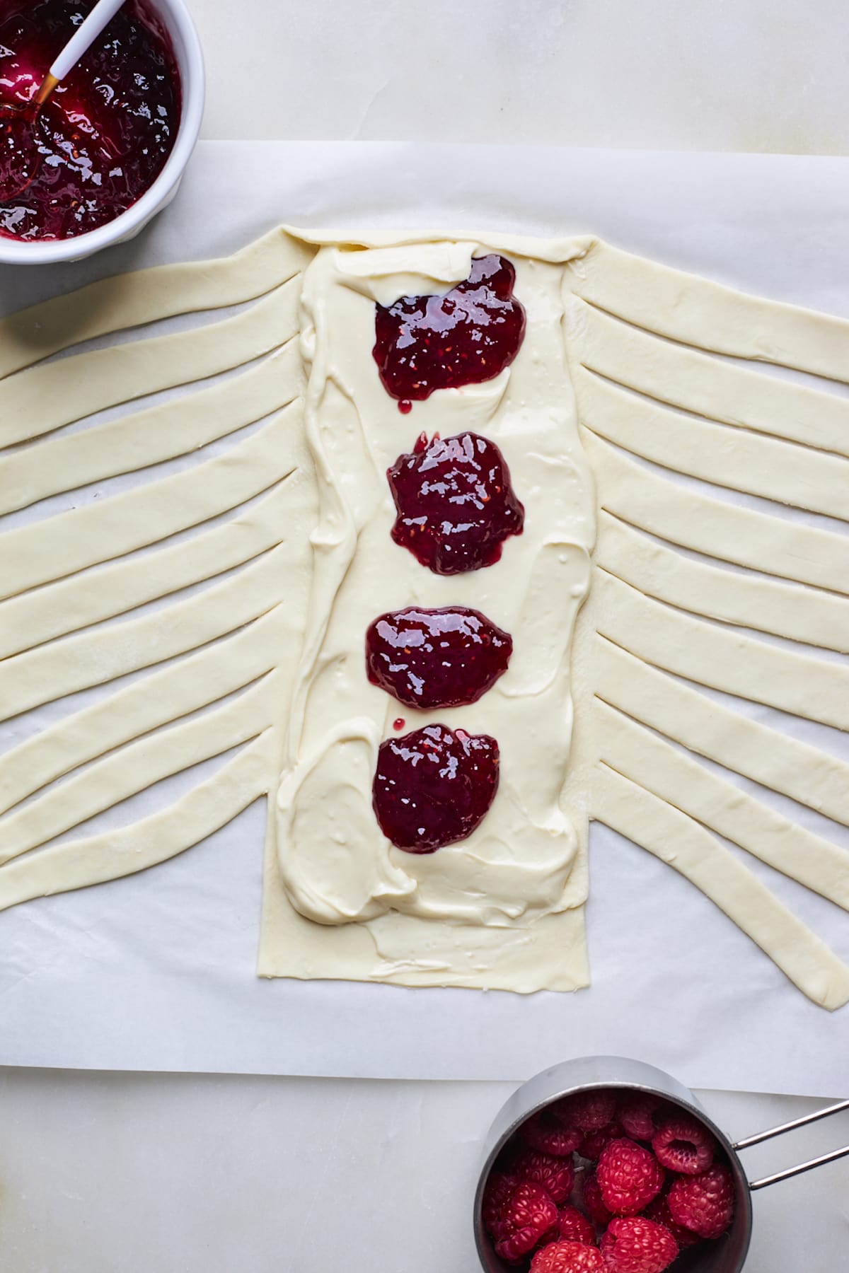 puff pastry with slits cut on the sides and cream cheese filling and raspberry jam in the center.