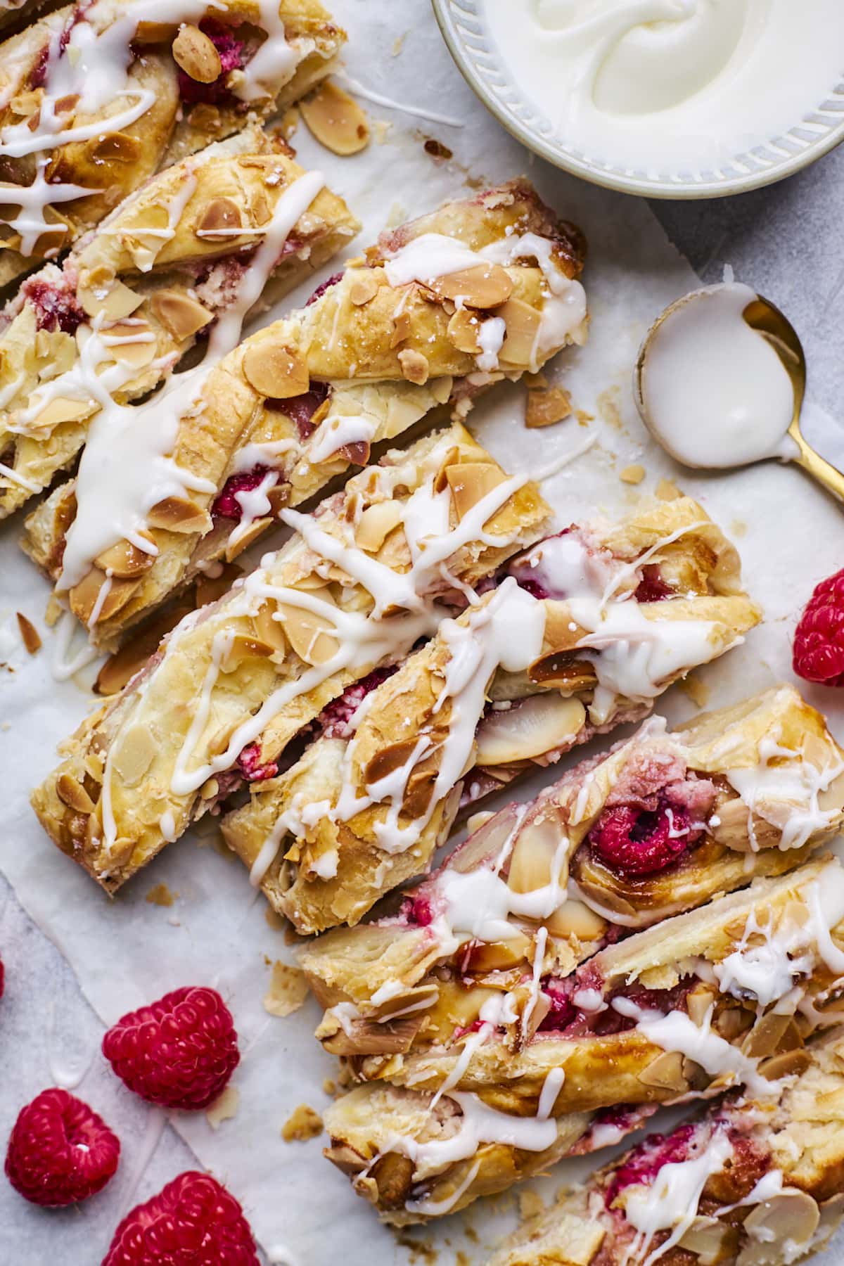 raspberry cream cheese breakfast braid cut into slices with almond glaze drizzled on top.