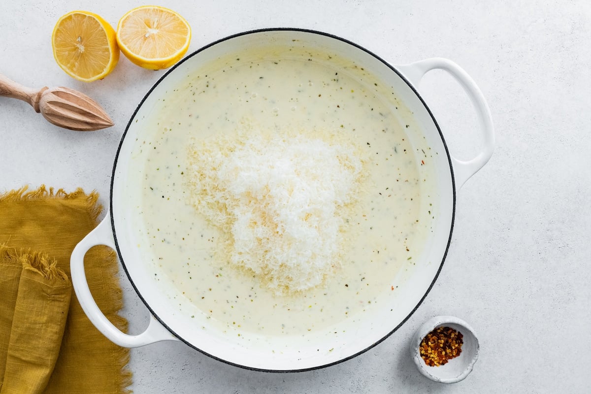 creamy pasta sauce in white pot with grated Parmesan cheese.