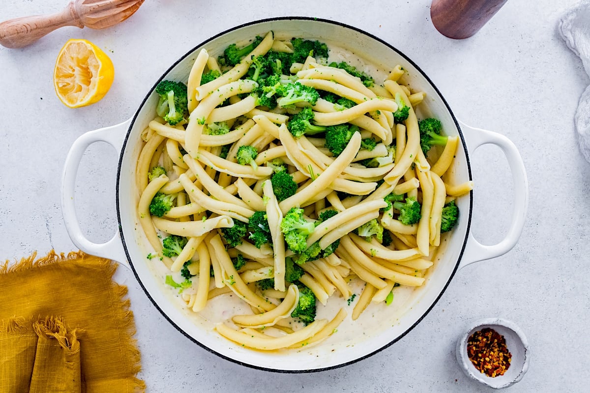 broccoli pasta in large white pot with cream sauce.