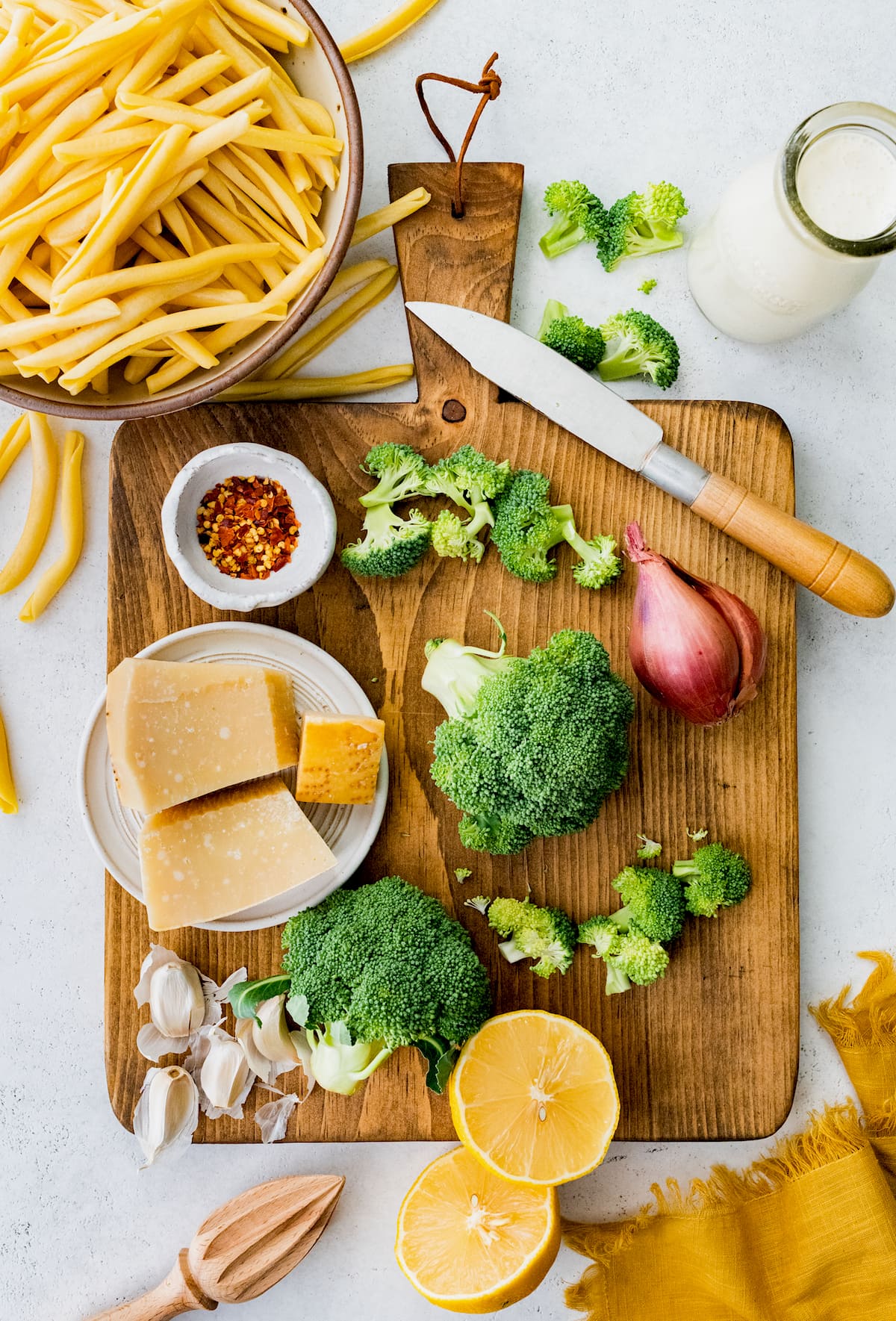 broccoli pasta ingredients on wood cutting board with knife.