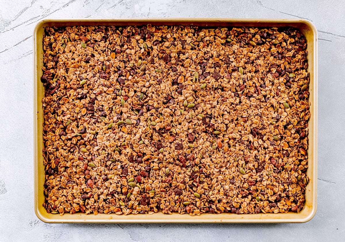 baked chocolate chip cookie granola cooling on large baking sheet.